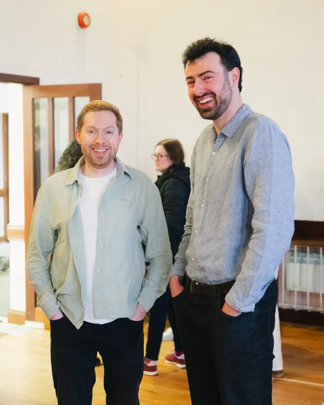 two men standing next to each other in a room