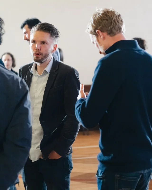 a group of people standing in a room talking to each other