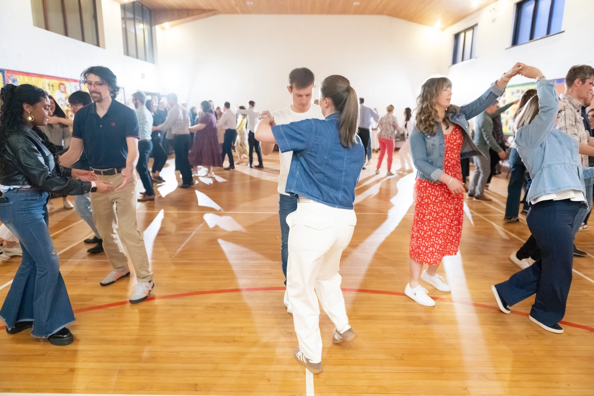 a group of people dancing on a wooden floor in a gymnasium