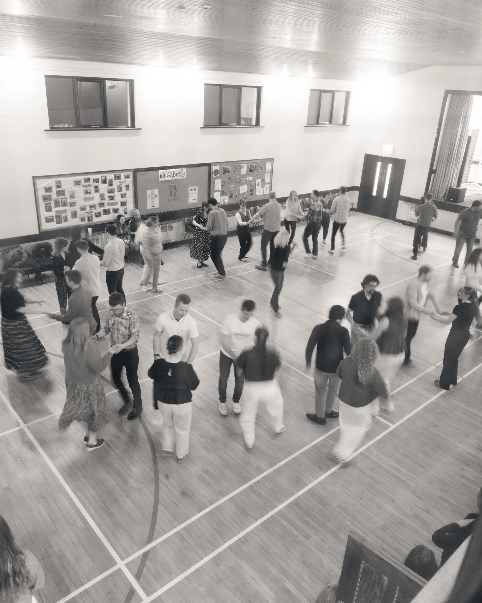 a group of people dancing on a wooden floor in a gymnasium