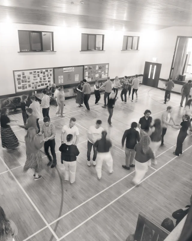 a group of people dancing on a wooden floor in a gymnasium