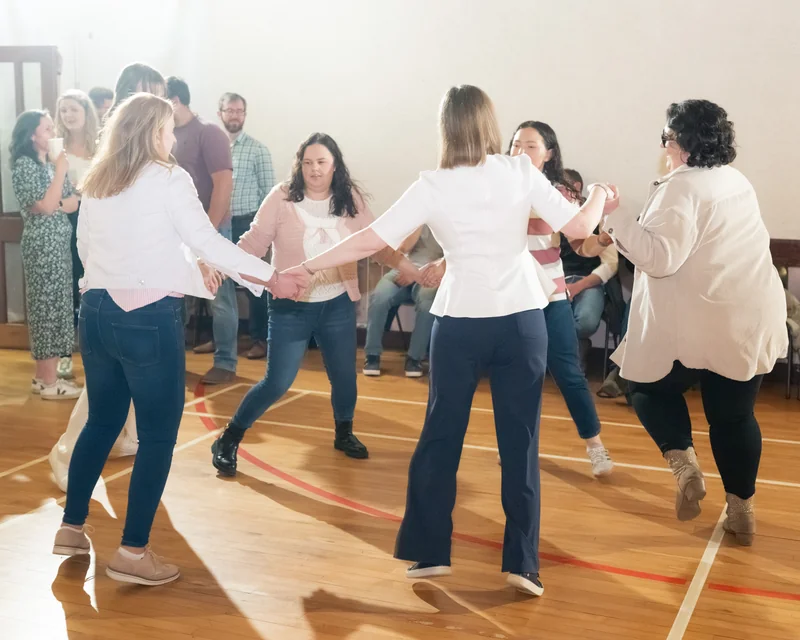 a group of people dancing in a circle on a wooden floor