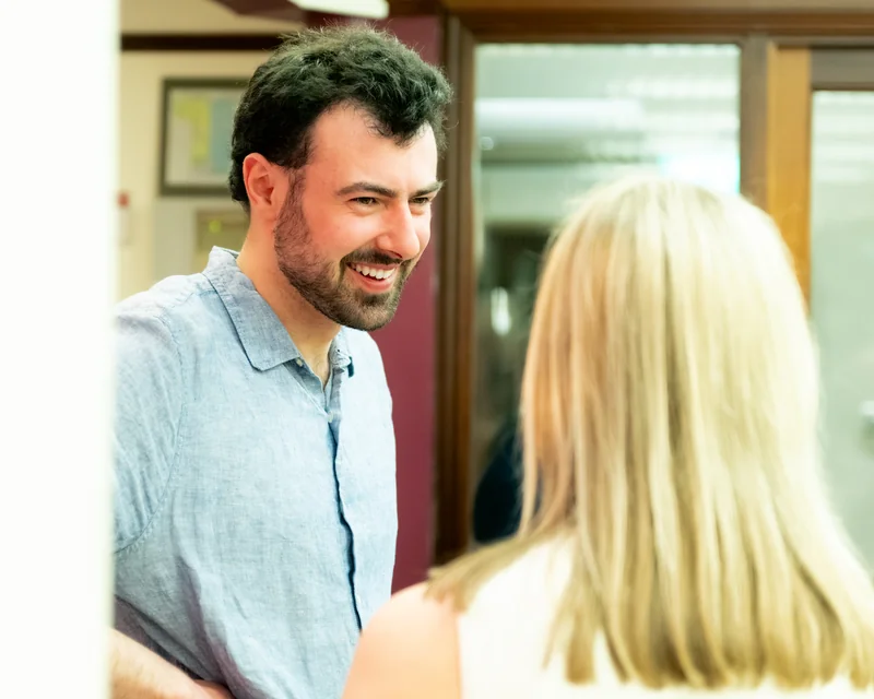 a man with a beard talking to a woman in a room