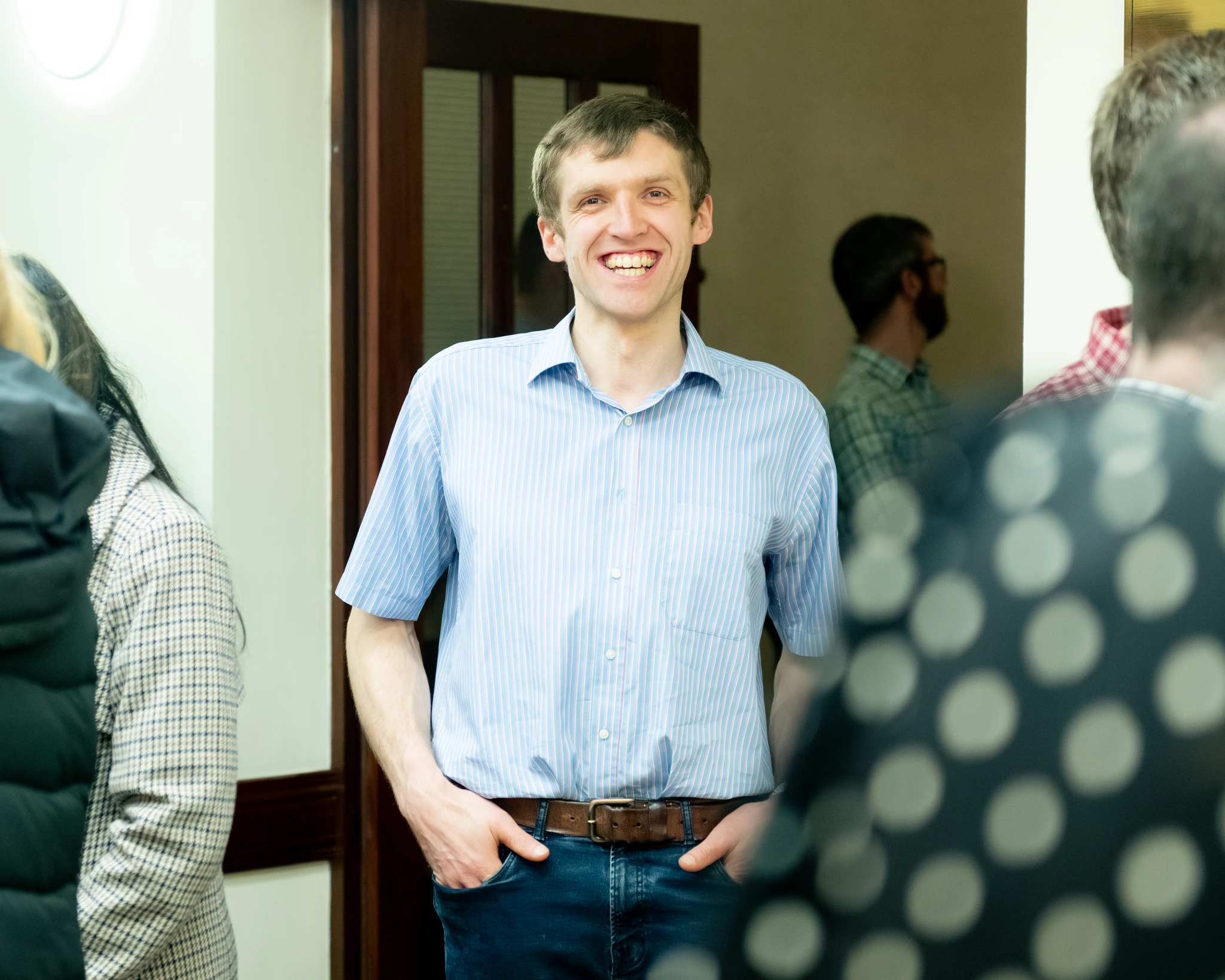 a man smiles as he stands in front of a crowd of people