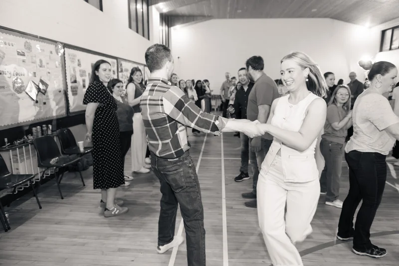 a man and woman dancing in a room full of people