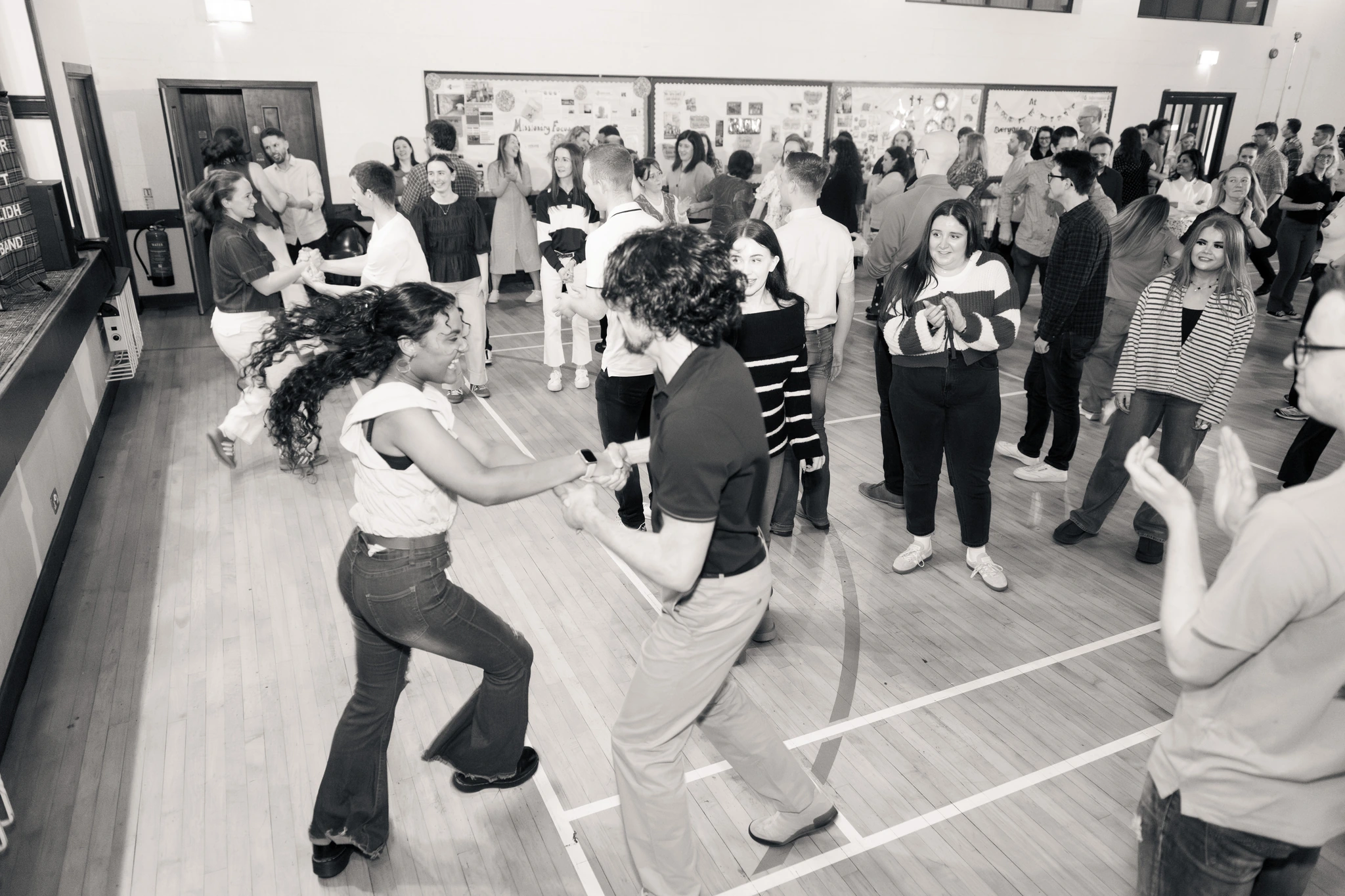 black and white photograph of a crowd of people dancing in a hall