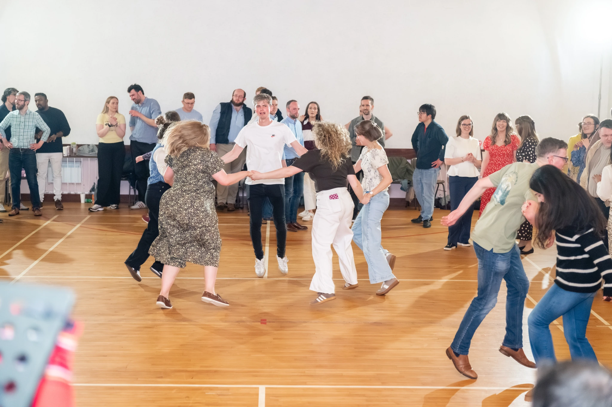a group of people dancing on a wooden floor in a room