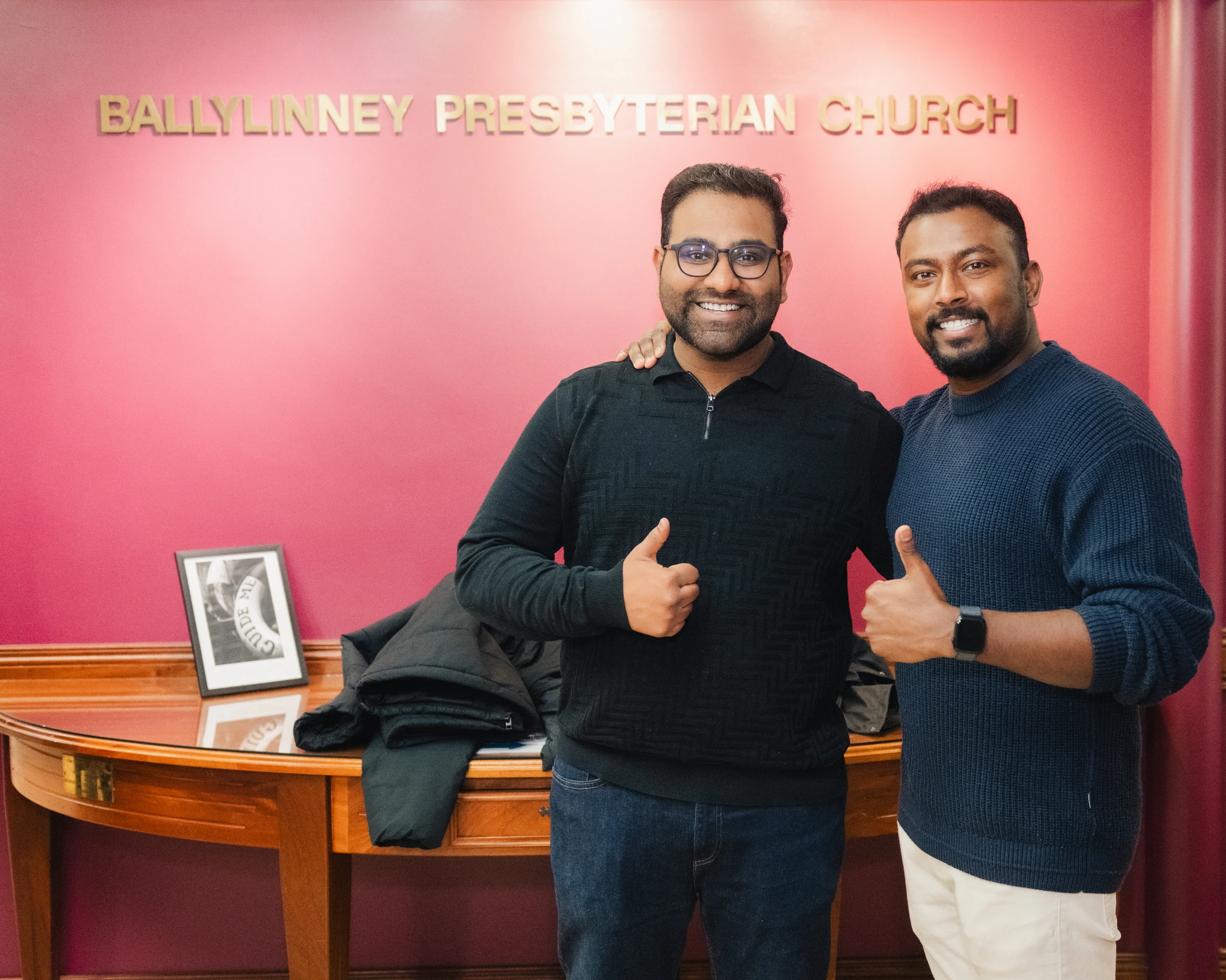 two men posing in front of a church