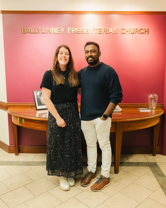 a man and woman standing in front of a church sign