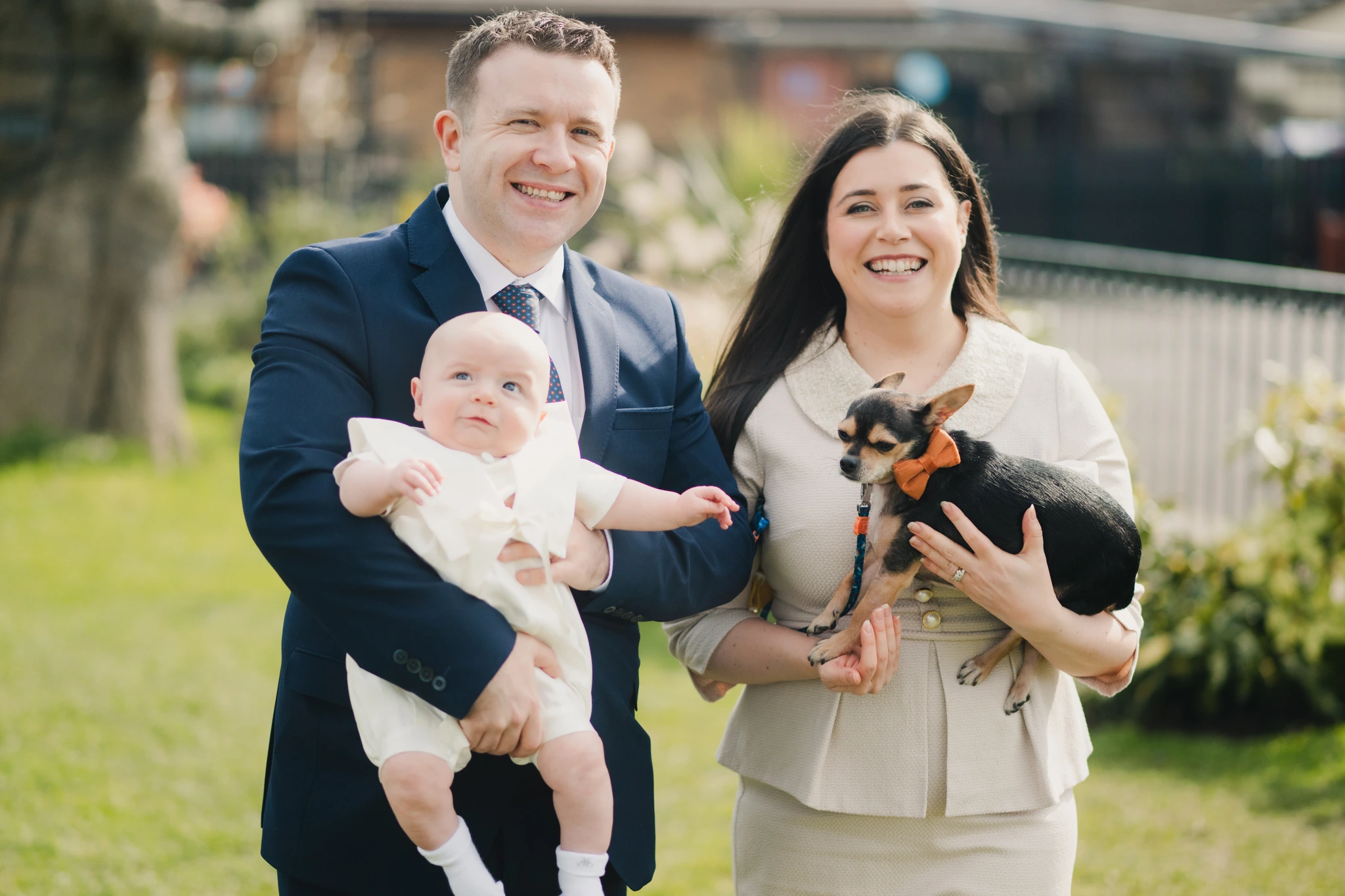 a man and woman in a suit and tie holding a baby in their arms