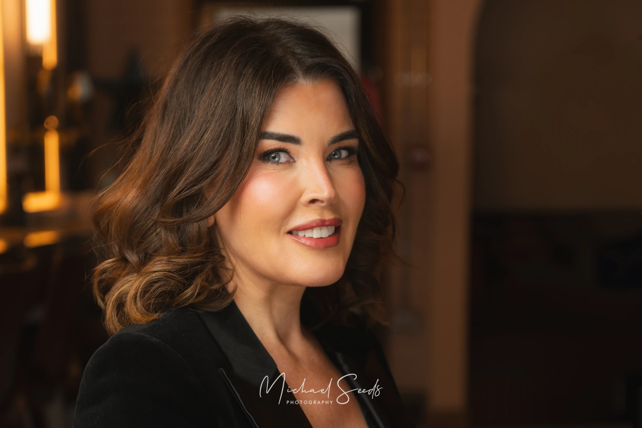 a woman in a black blazer with a smile on her face