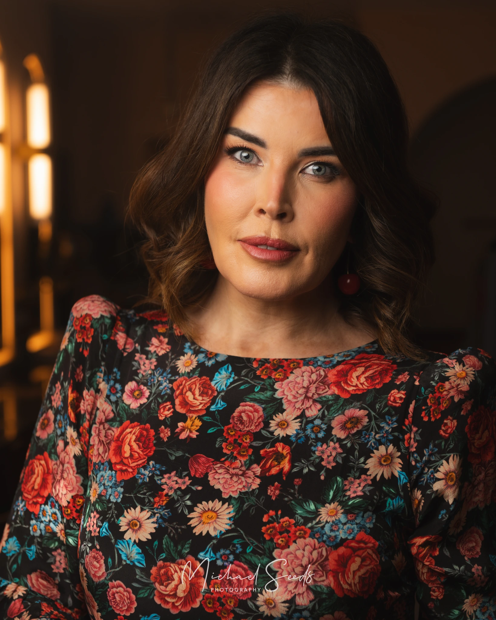 a woman in a floral dress is standing in front of a window