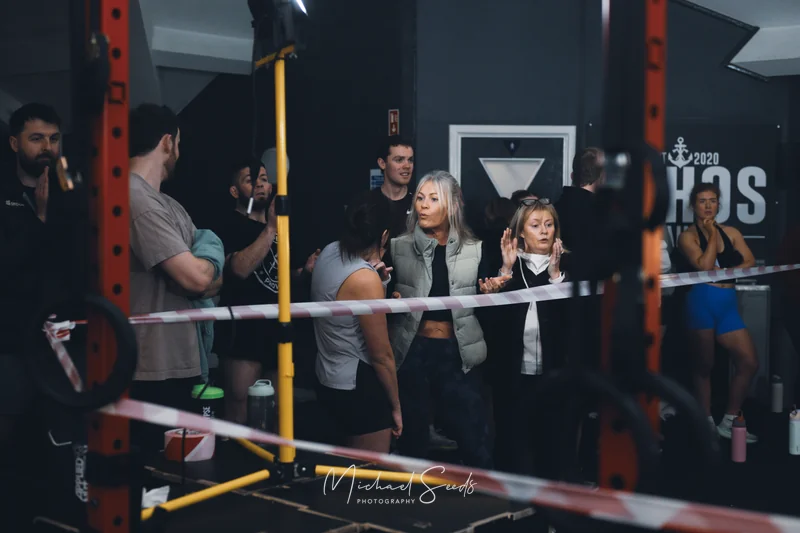 a group of people standing in front of a barbell in a gym