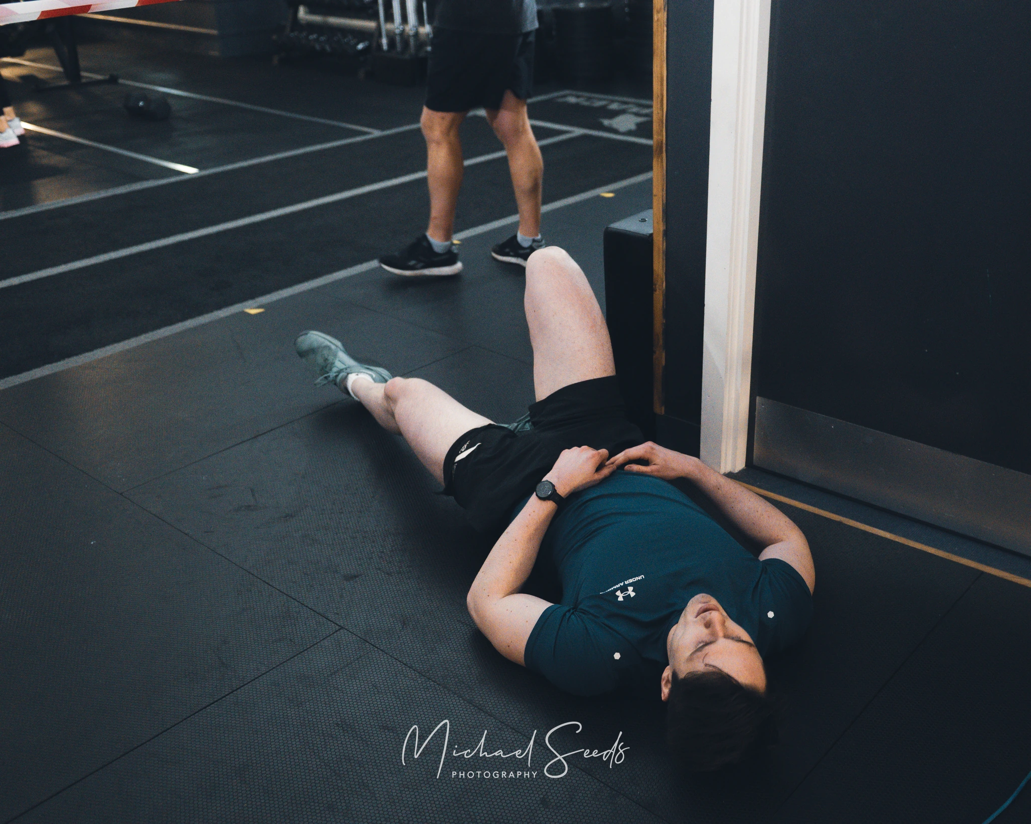 a man laying on the floor in front of a rowing machine in a gym