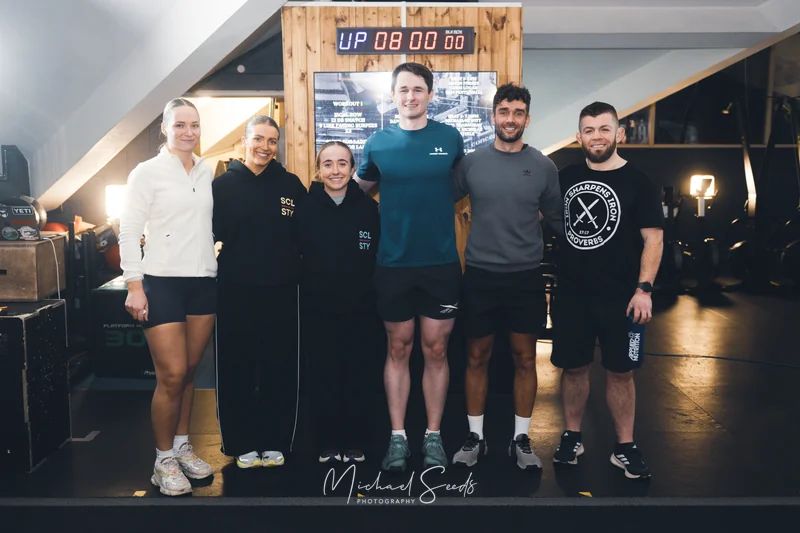 a group of people standing next to a clock in a gym