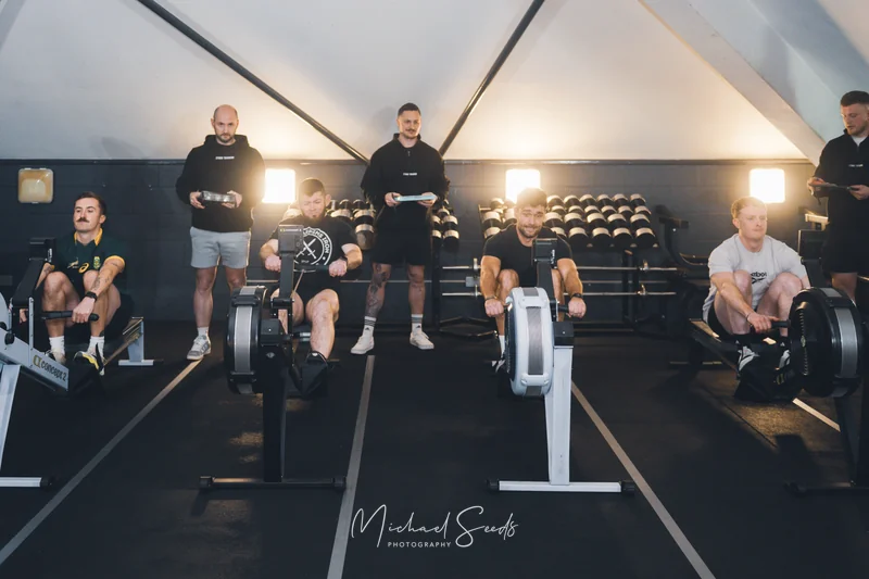a group of people sitting in a row of rowing machines