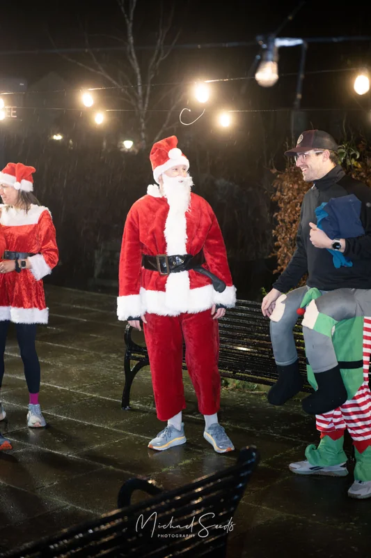 a group of people dressed up as santa claus on a park bench