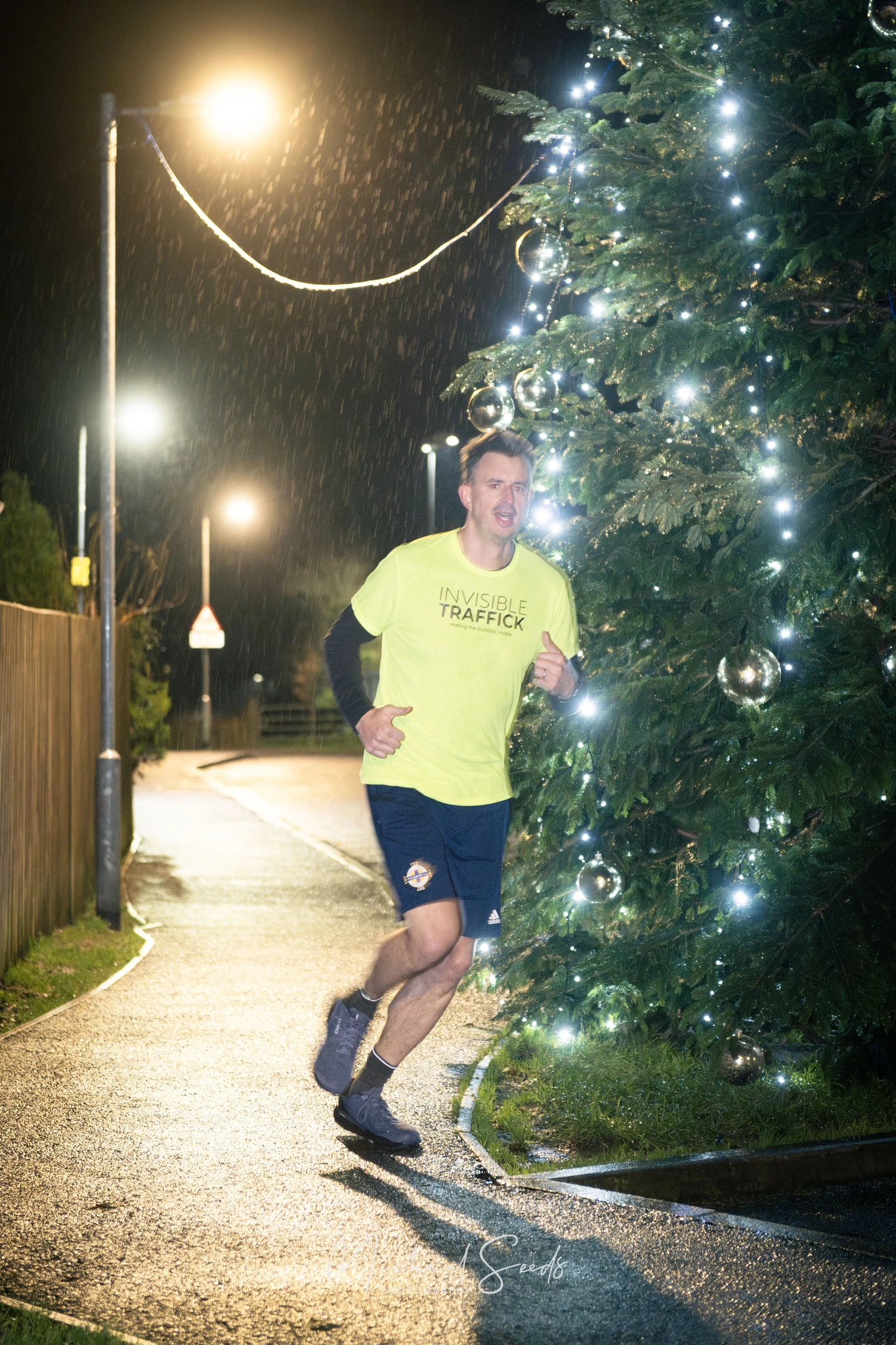 a man running in front of a christmas tree at night