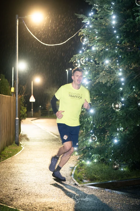 a man running in front of a christmas tree at night
