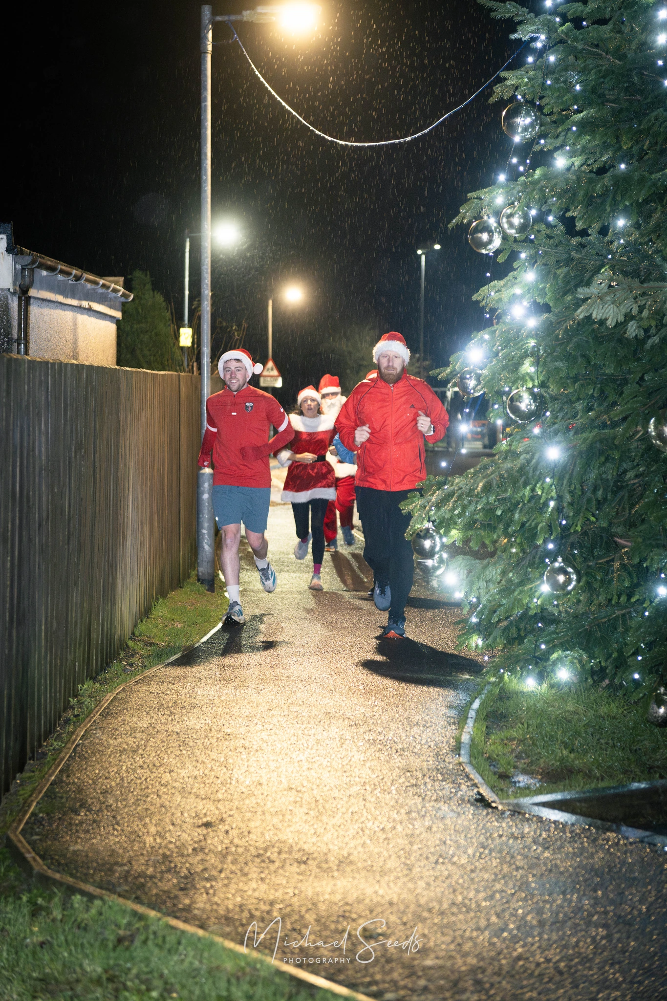 a group of people running down a street at night