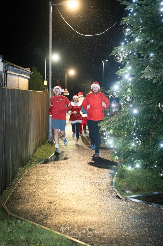 a group of people running down a street at night