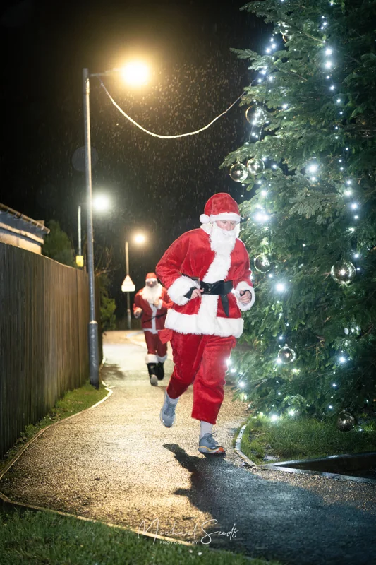 santa claus runs down a street at night