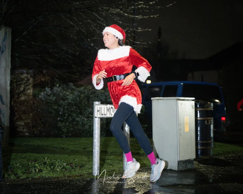 a woman dressed as santa running down a street