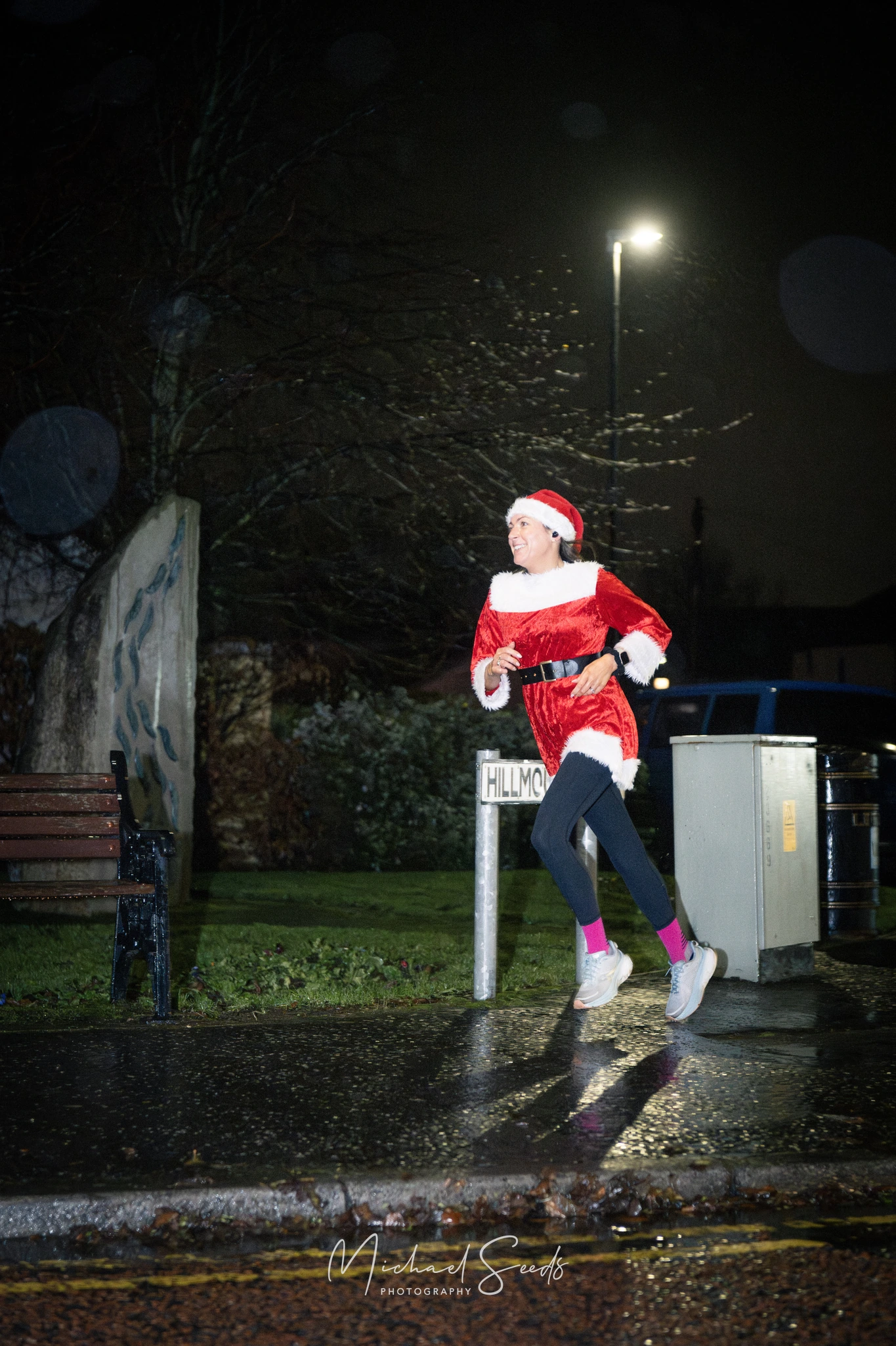 a woman dressed as santa running down a street at night