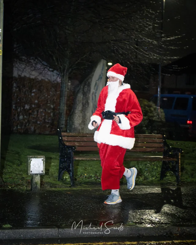 a man dressed as santa runs down a street
