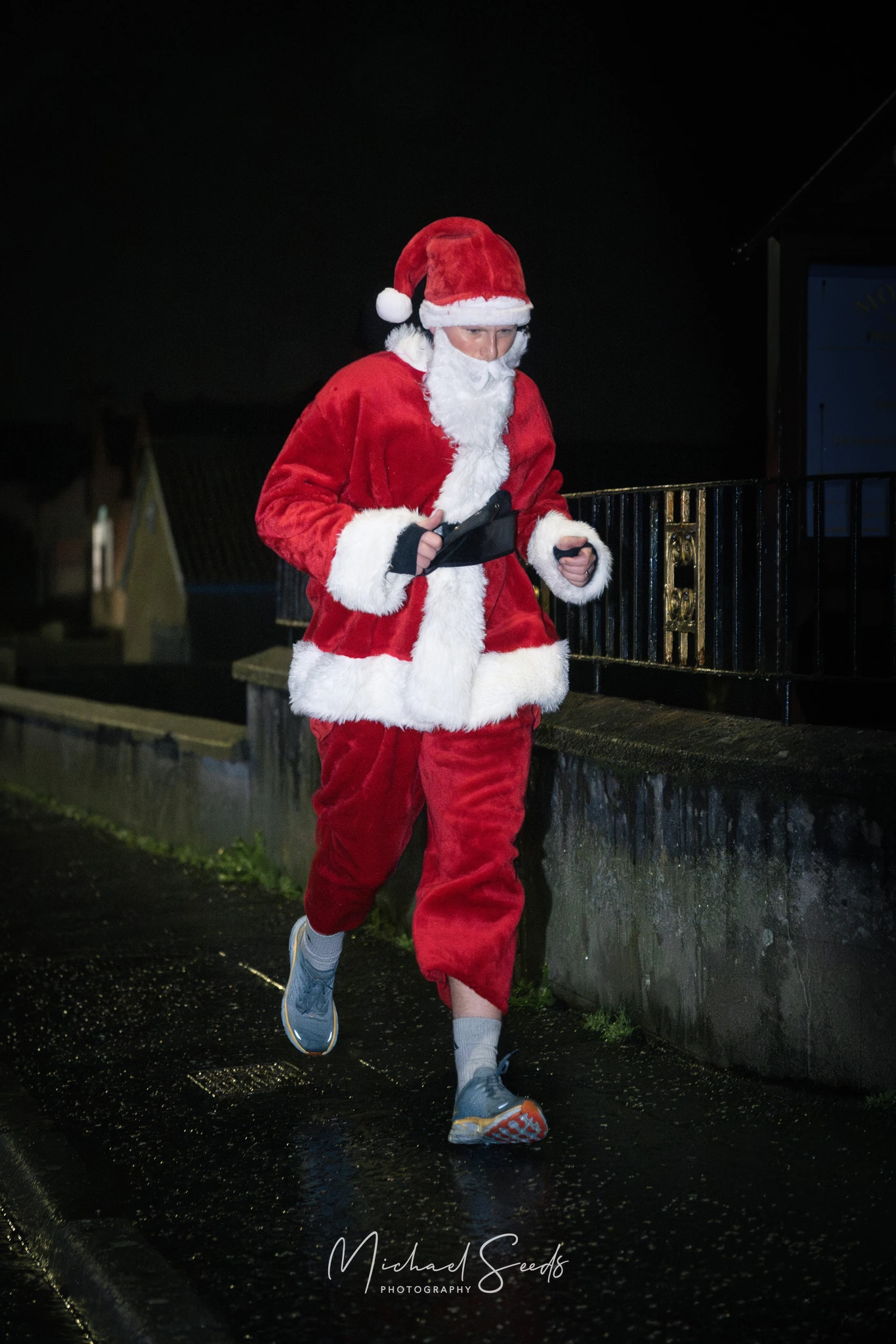 a man dressed as santa running down a street at night