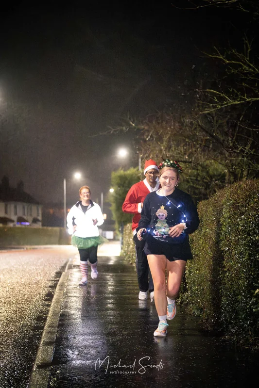 a group of people running down a street at night