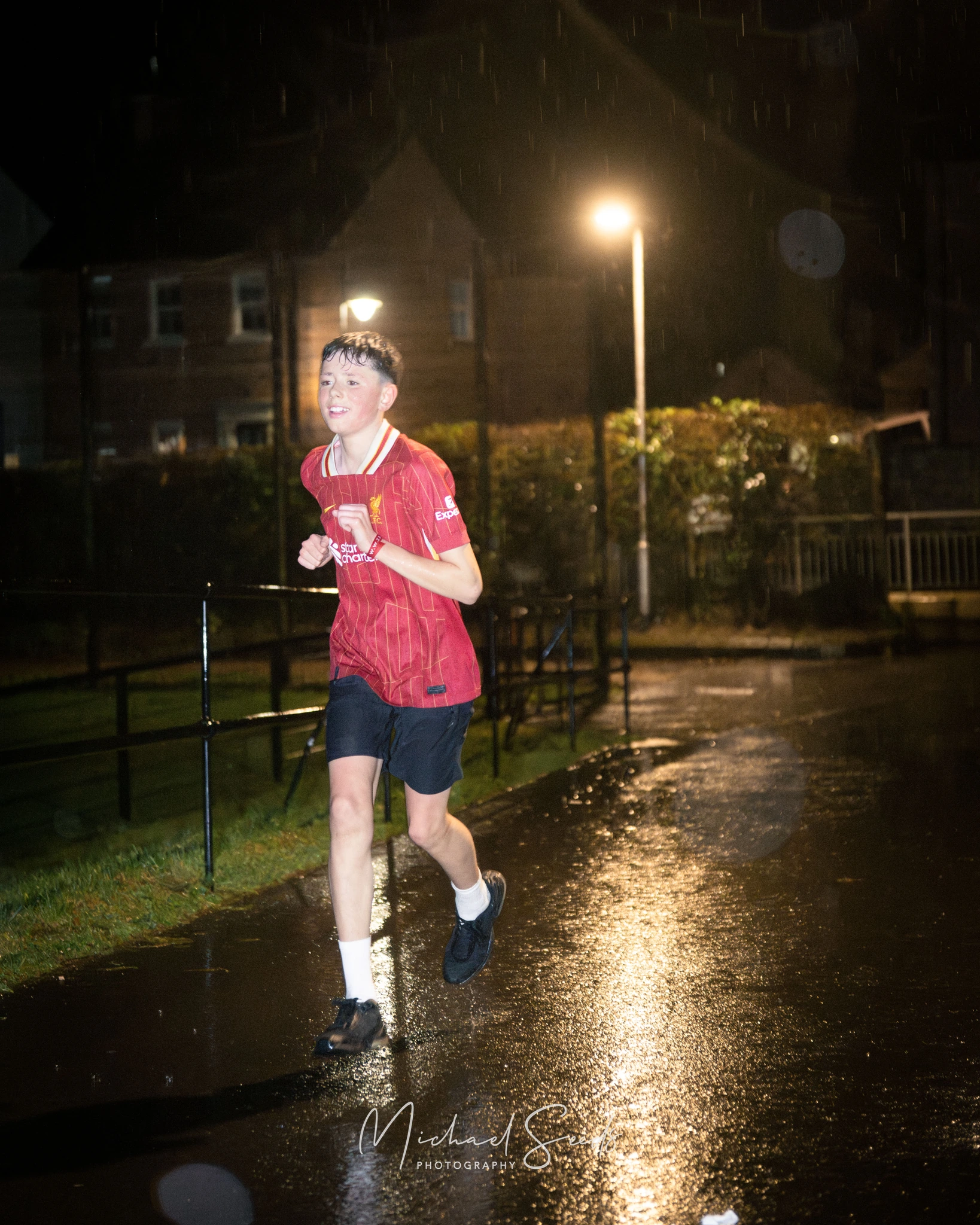 a young man running down a street in the rain at night
