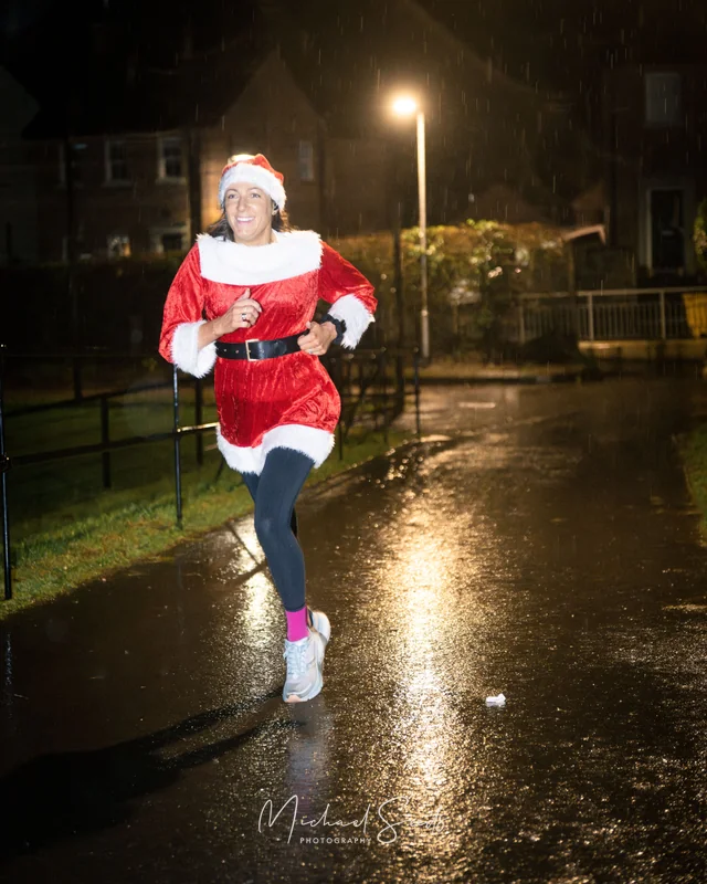 a woman dressed as santa running in the rain