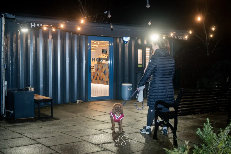a woman walking her dog at night in front of a shipping container