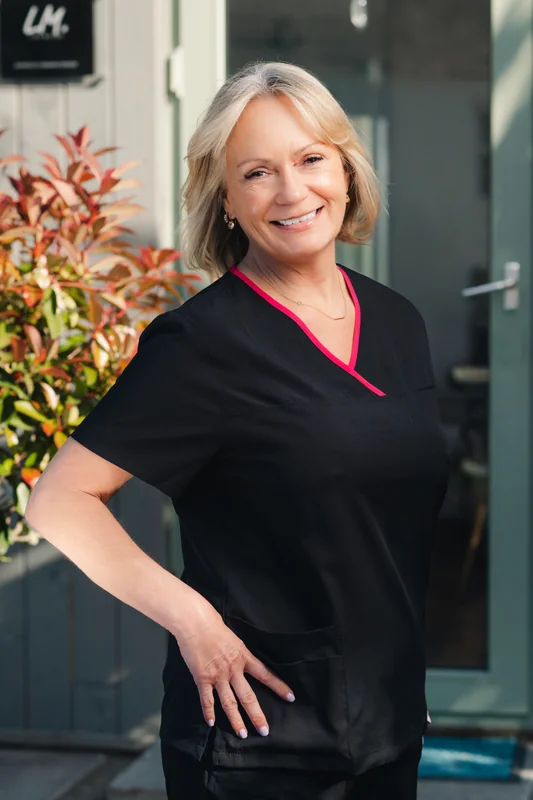 a woman in black scrubs standing in front of a doorway