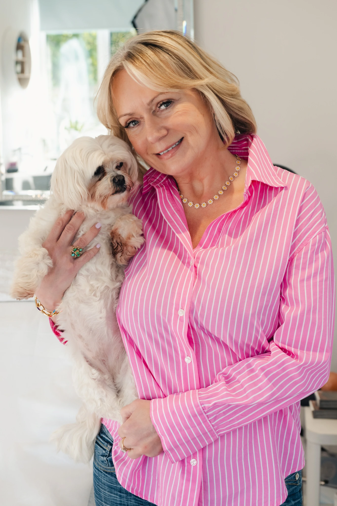 a woman in a pink shirt holding a small white dog