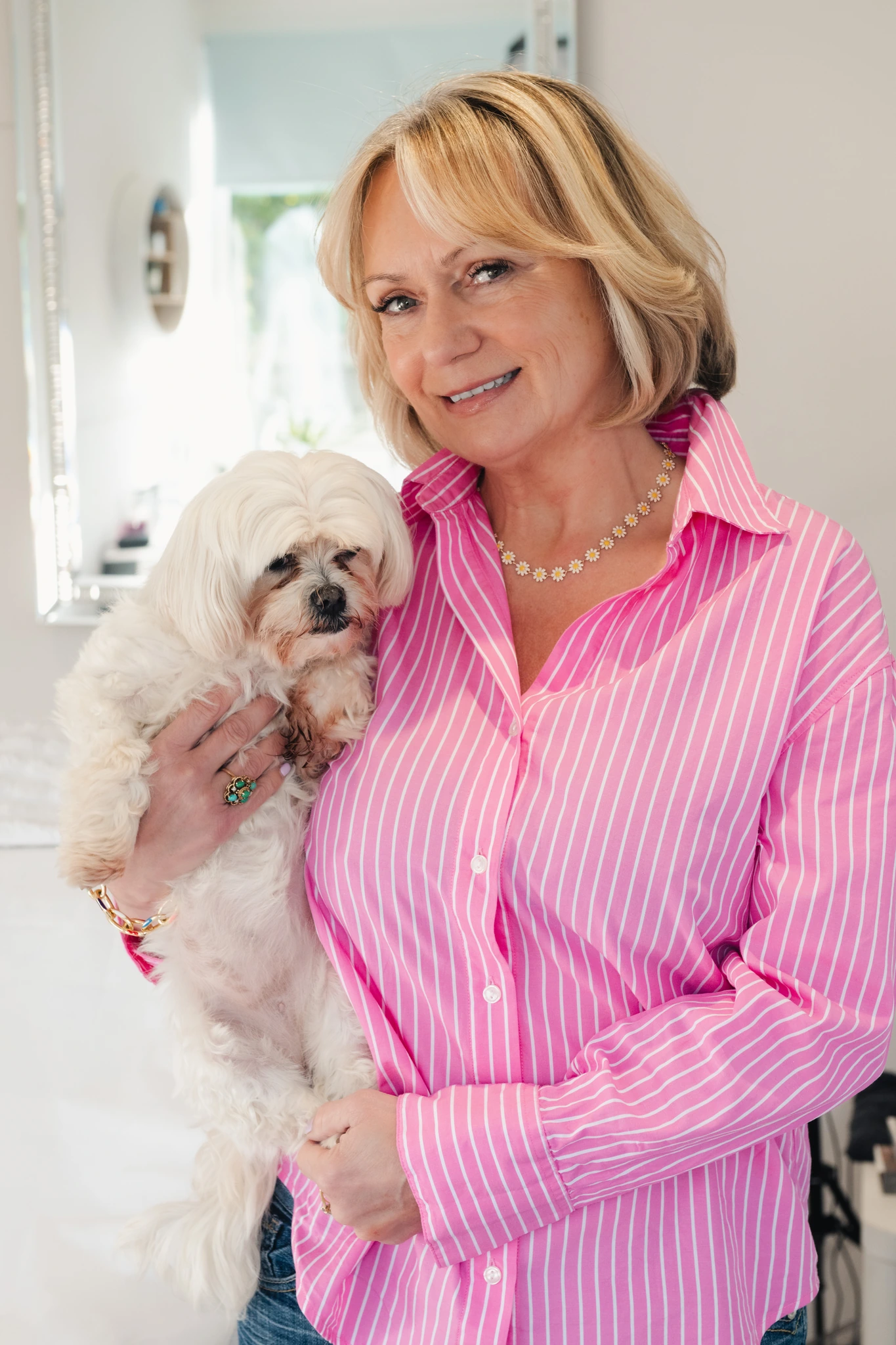 a woman in a pink shirt holding a small white dog