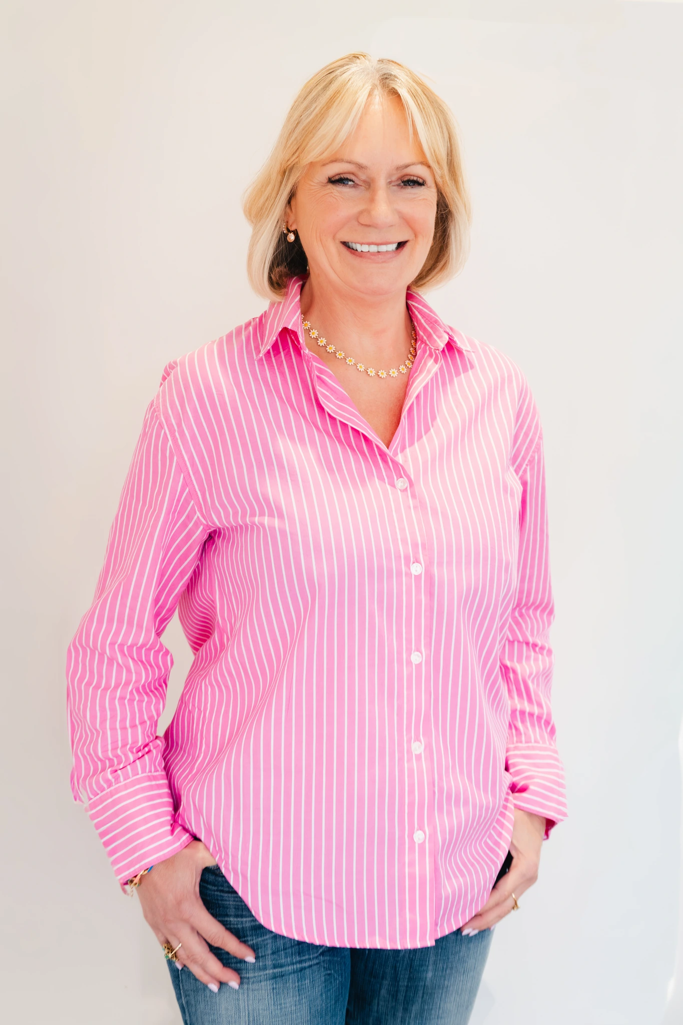 a woman wearing a pink striped shirt and jeans