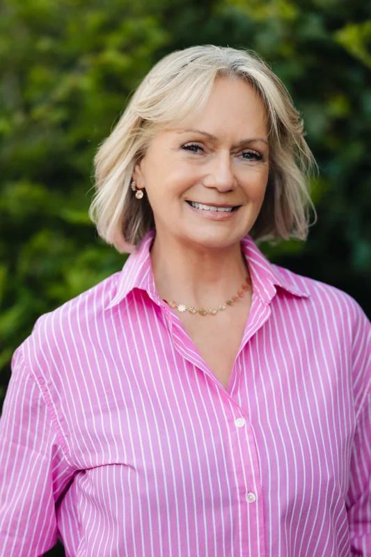 a woman in a pink shirt with a smile on her face
