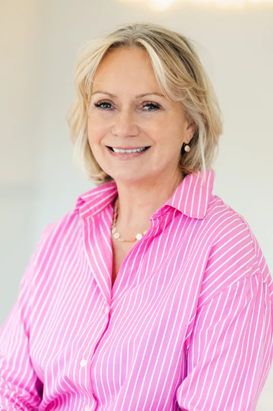 a woman in a pink shirt with a smile on her face