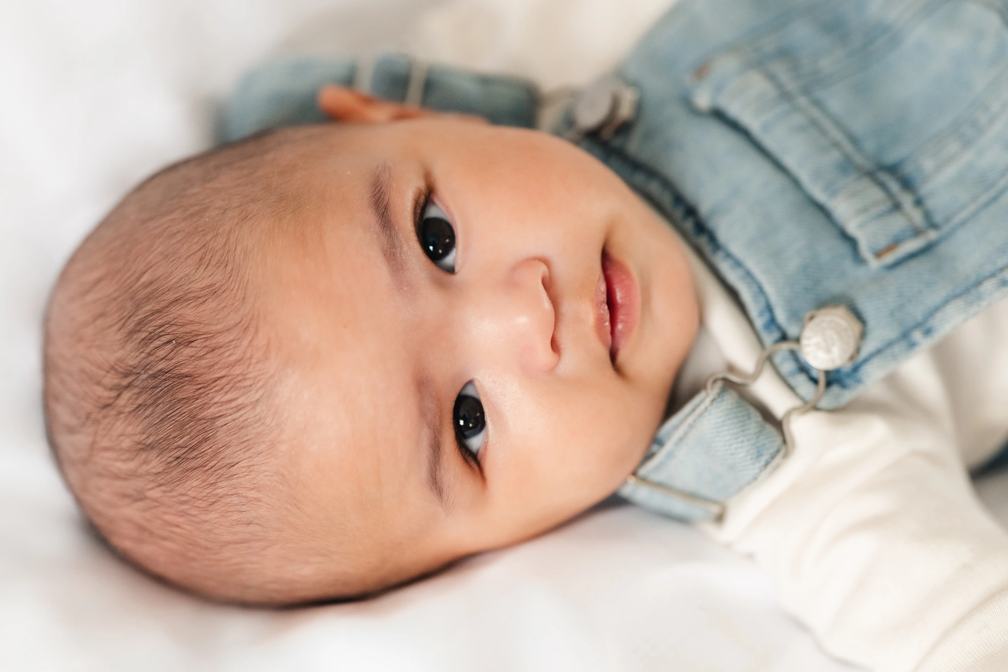 a baby boy is lying on a bed with his eyes wide open