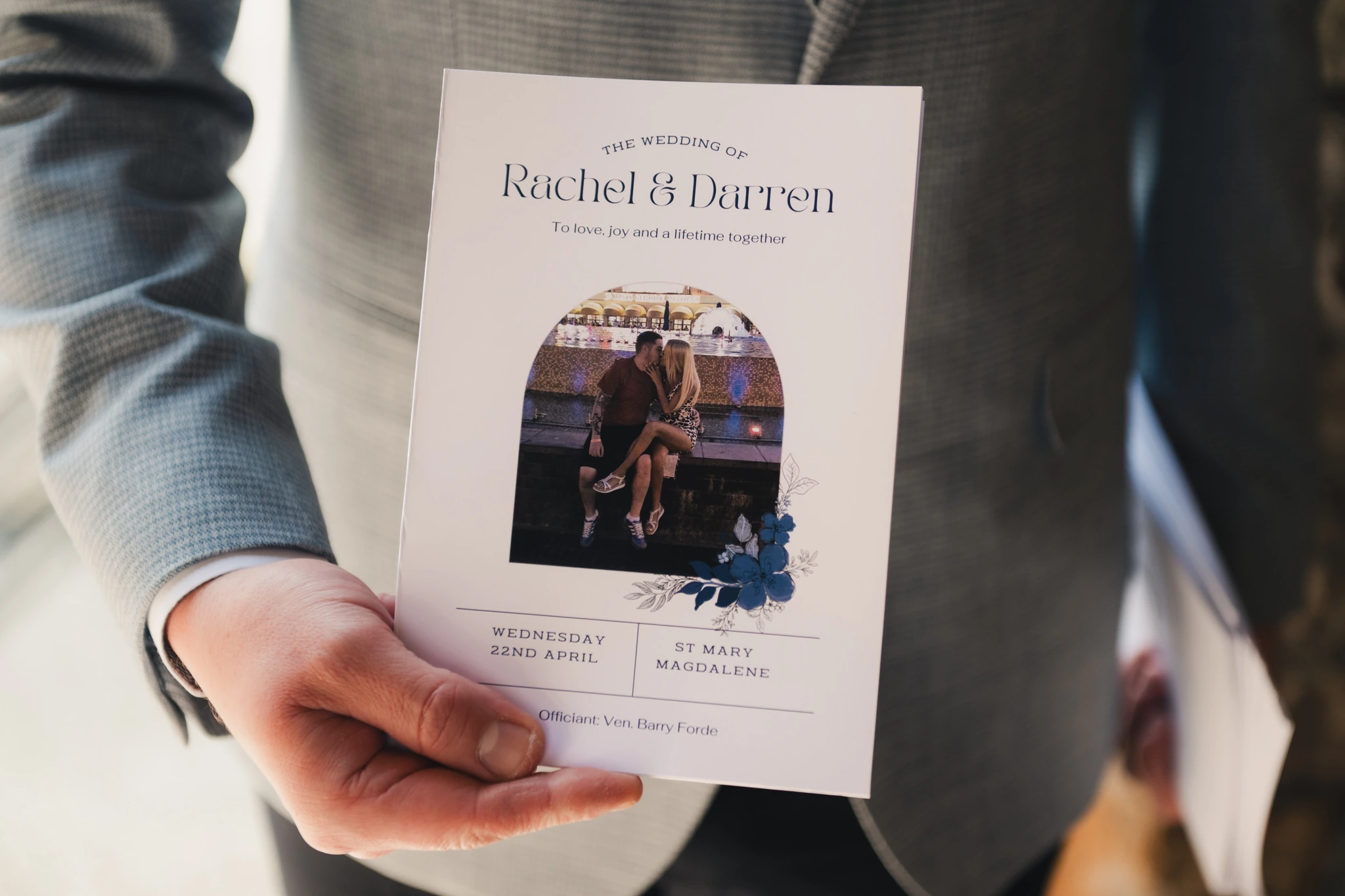a man in a suit holds up a wedding program