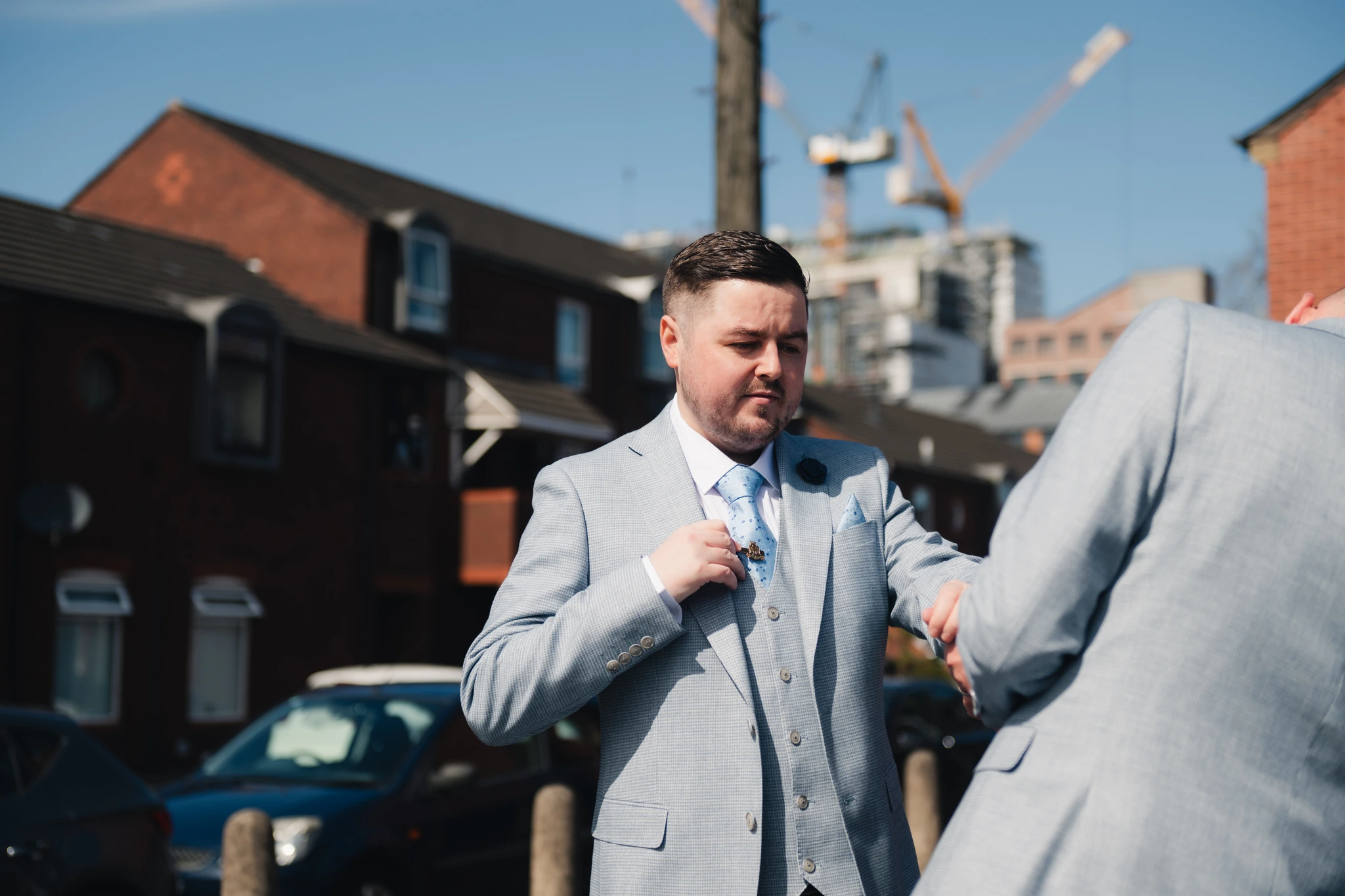a man in a suit and tie is putting on a tie