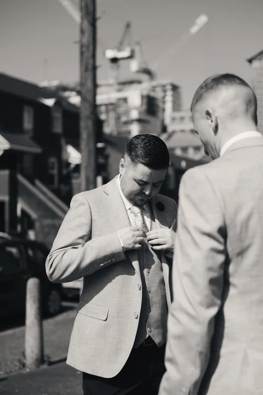 a man in a suit with a tie and cufflinks is standing on a street corner