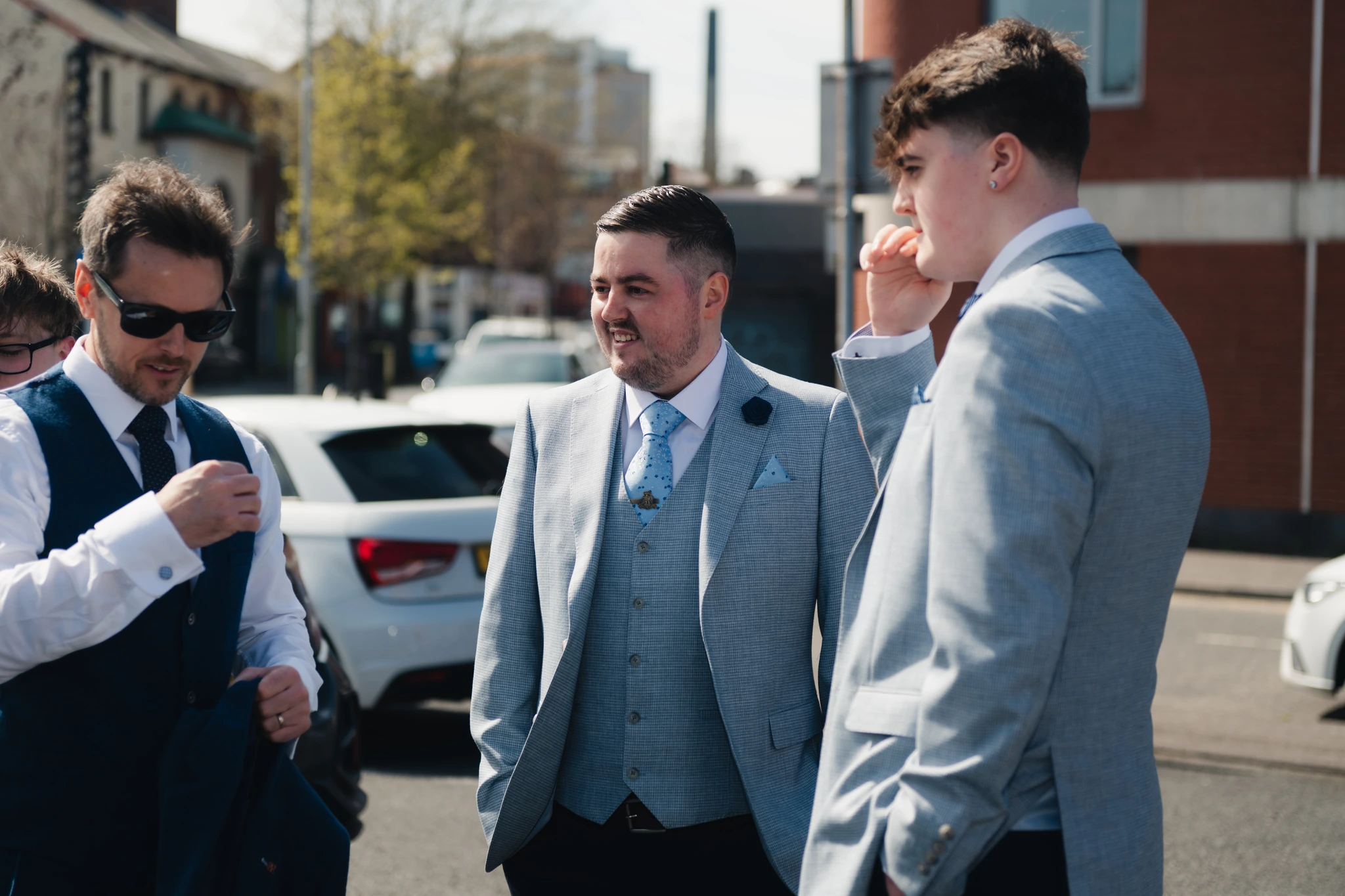 a group of men in suits and hats talking to each other on a street