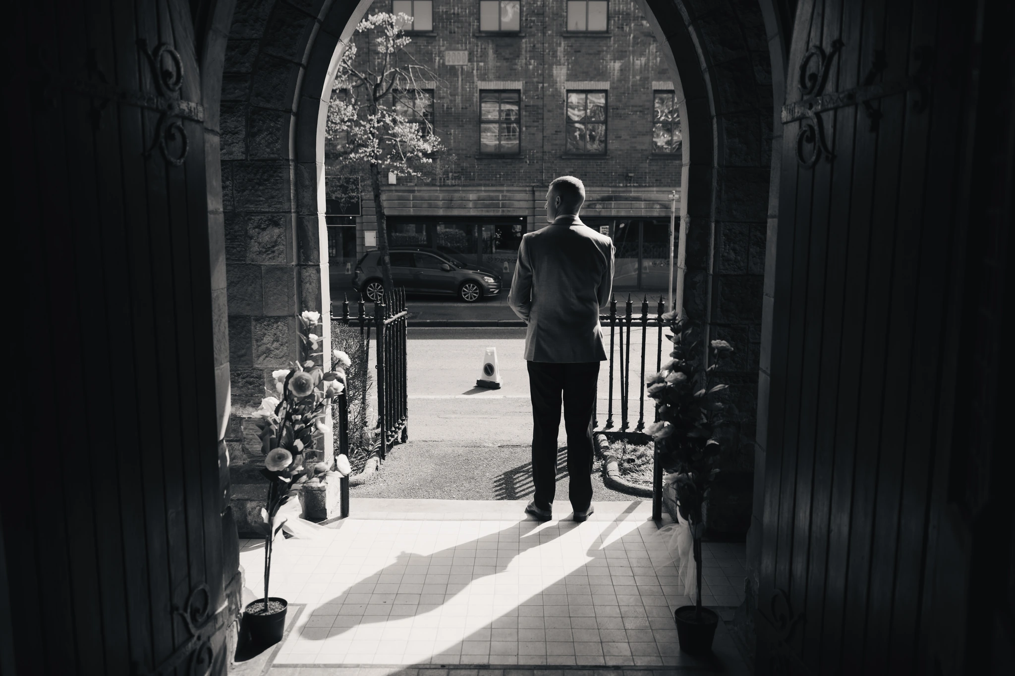 a black and white image of a man standing in a doorway