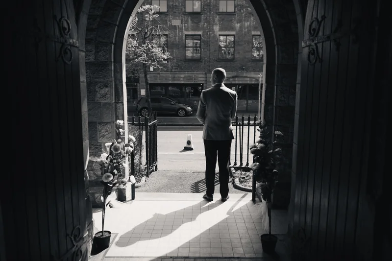 a black and white image of a man standing in a doorway