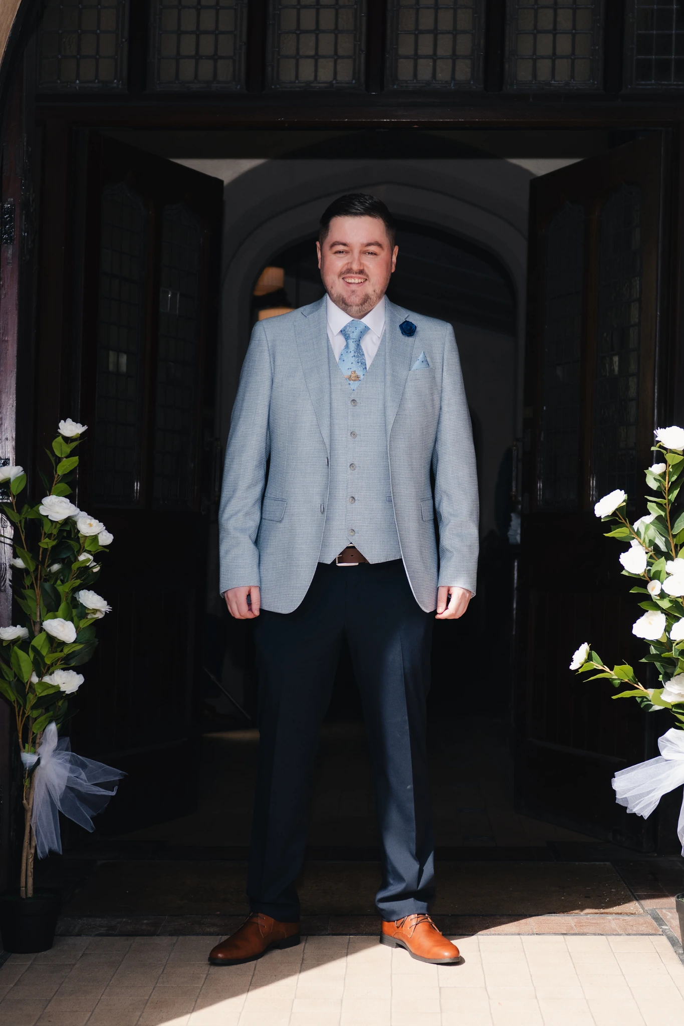 a man in a suit standing in front of a doorway
