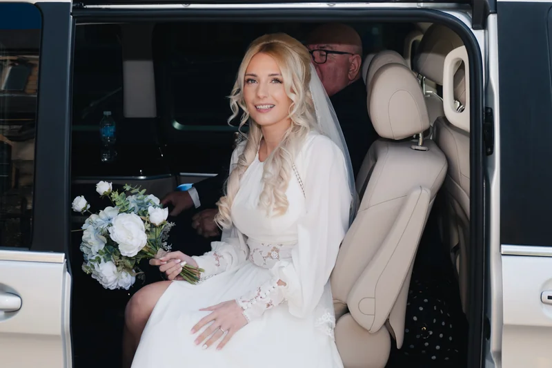 a bride sitting in the back seat of a wedding car