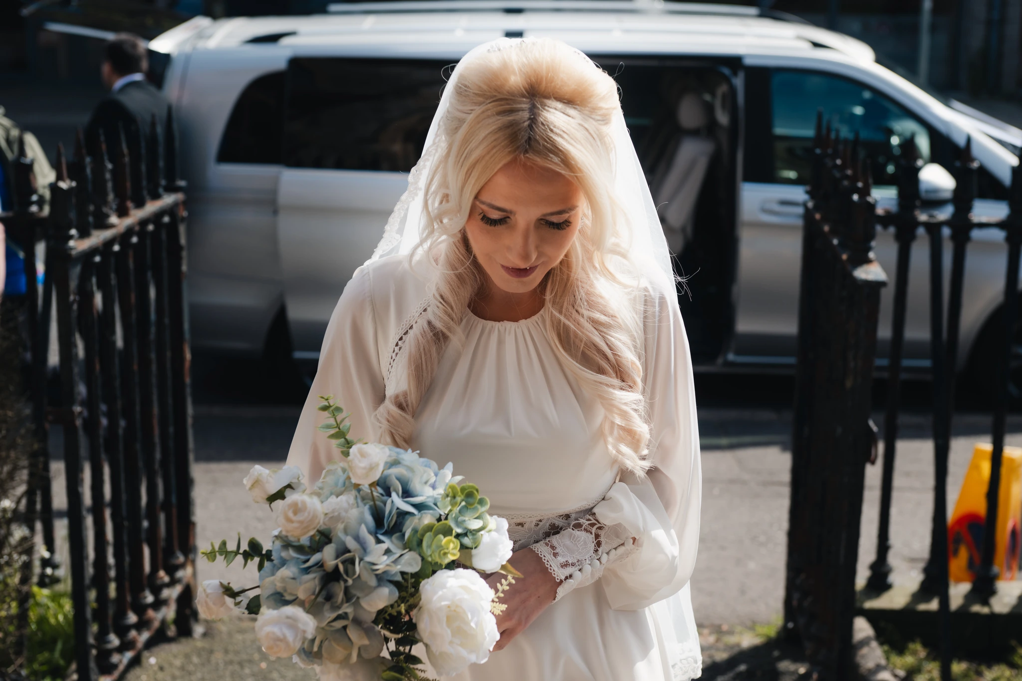 a bride walks down a street with her wedding bouquet
